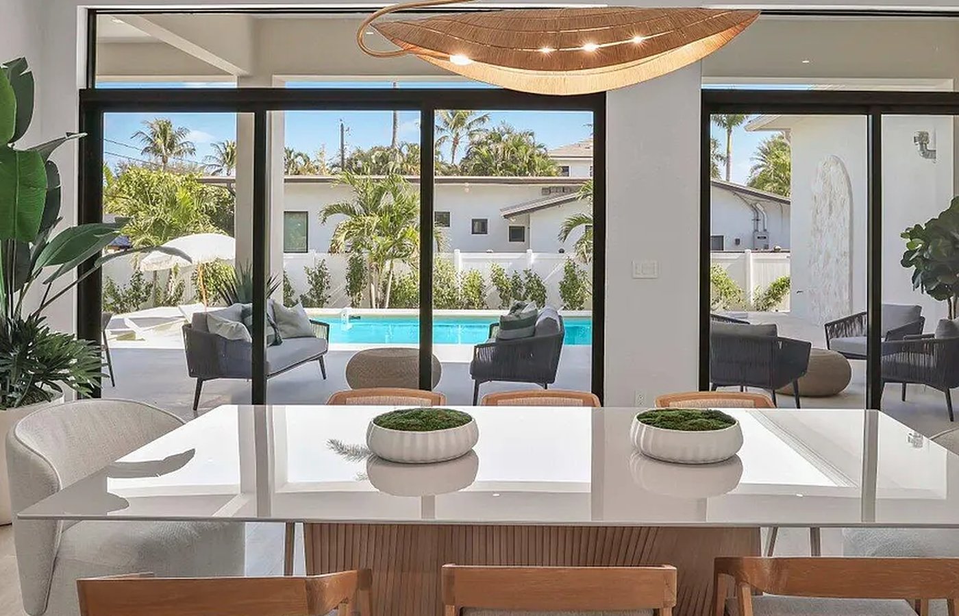 Custom pool with indoor-outdoor lounge furniture and palm trees in a Delray Beach home, by Acassa