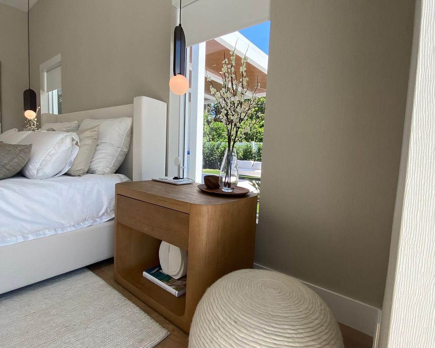 Primary bedroom in the Roth Romano residence with view through window to back-yard pergola and South Florida landscaping