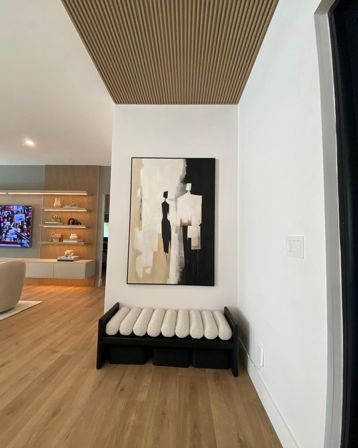 Slatted wood ceiling, sculptural bench, and oversized art in the Roth Romano whole-home renovation