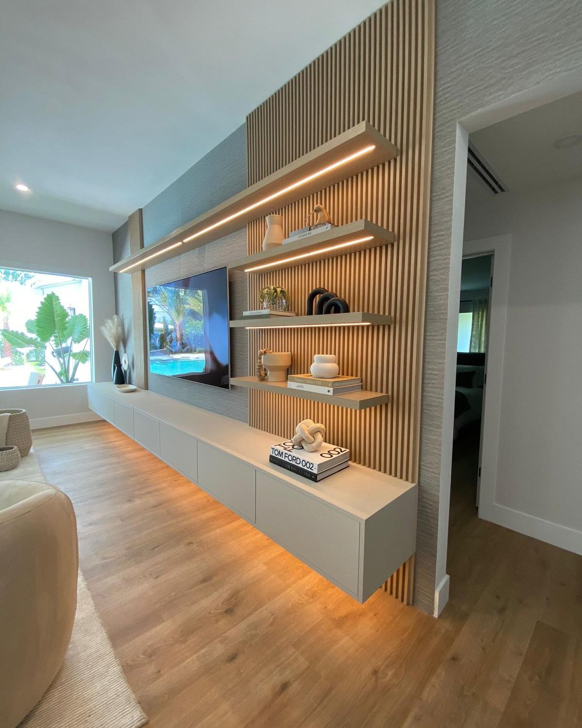 Built-in TV wall with slatted wood detail and floating shelves