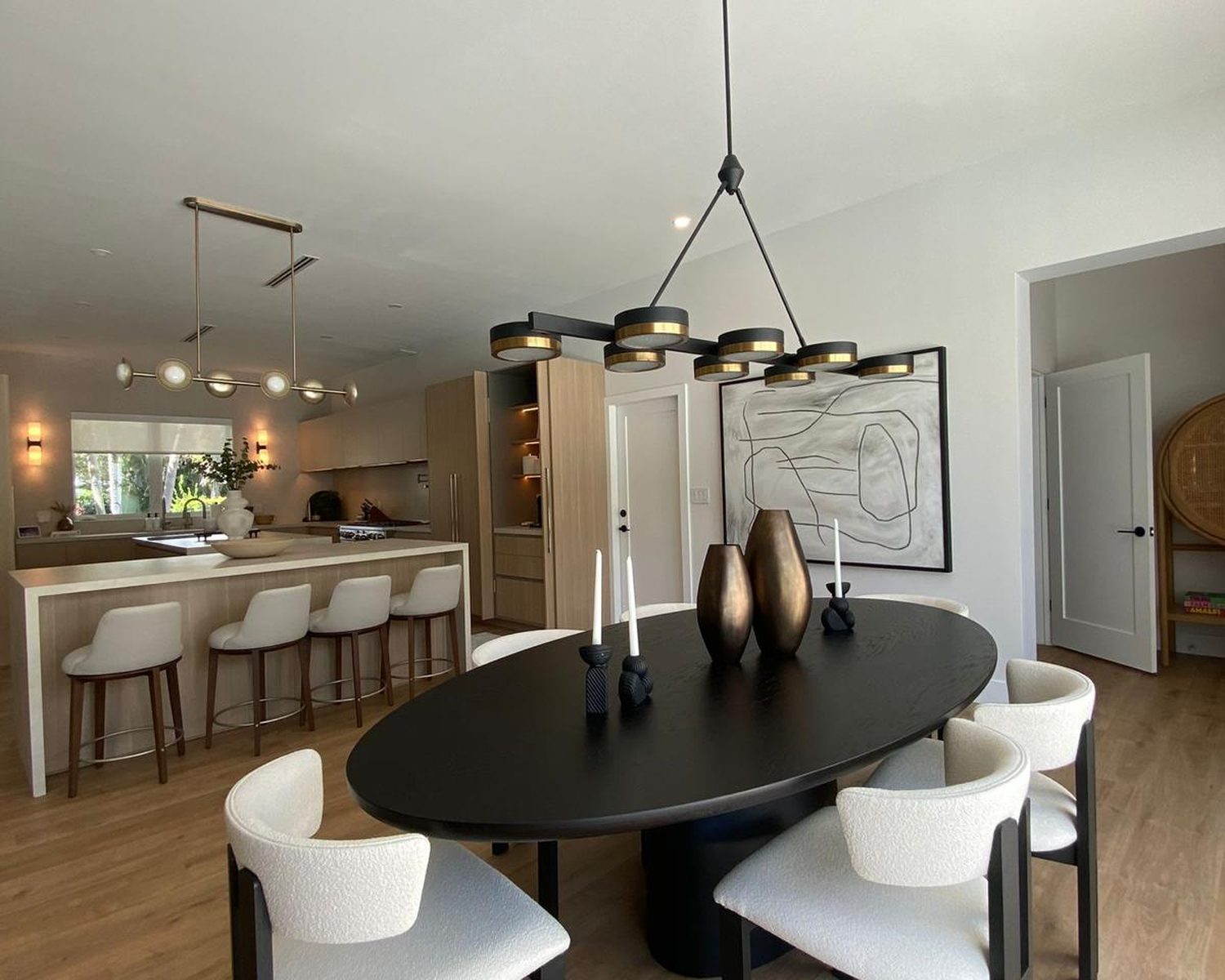 Open-plan dining and kitchen in a whole-home renovation, with modern chandelier and white boucle seating