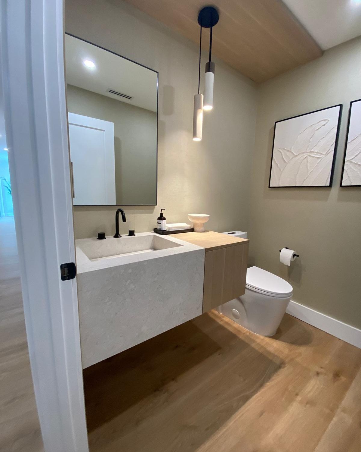 Sculptural stone vanity in a powder room with pendant lighting and white oak floor