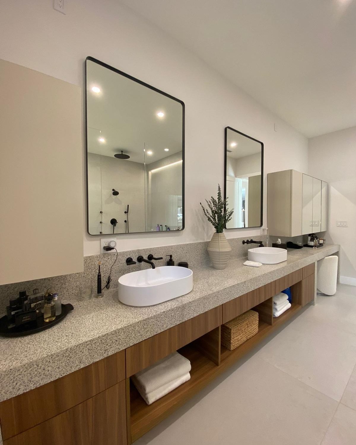 Double-vanity primary bath with terrazzo countertop and walnut cabinetry
