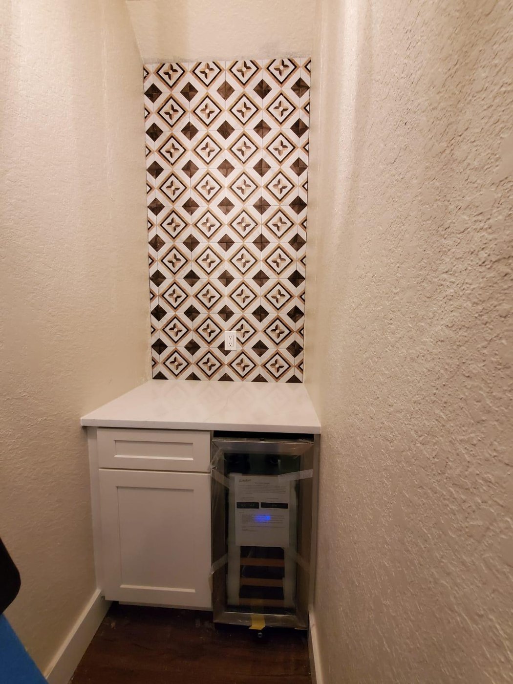 Custom dry bar with built-in wine fridge and full-height patterned tile backsplash