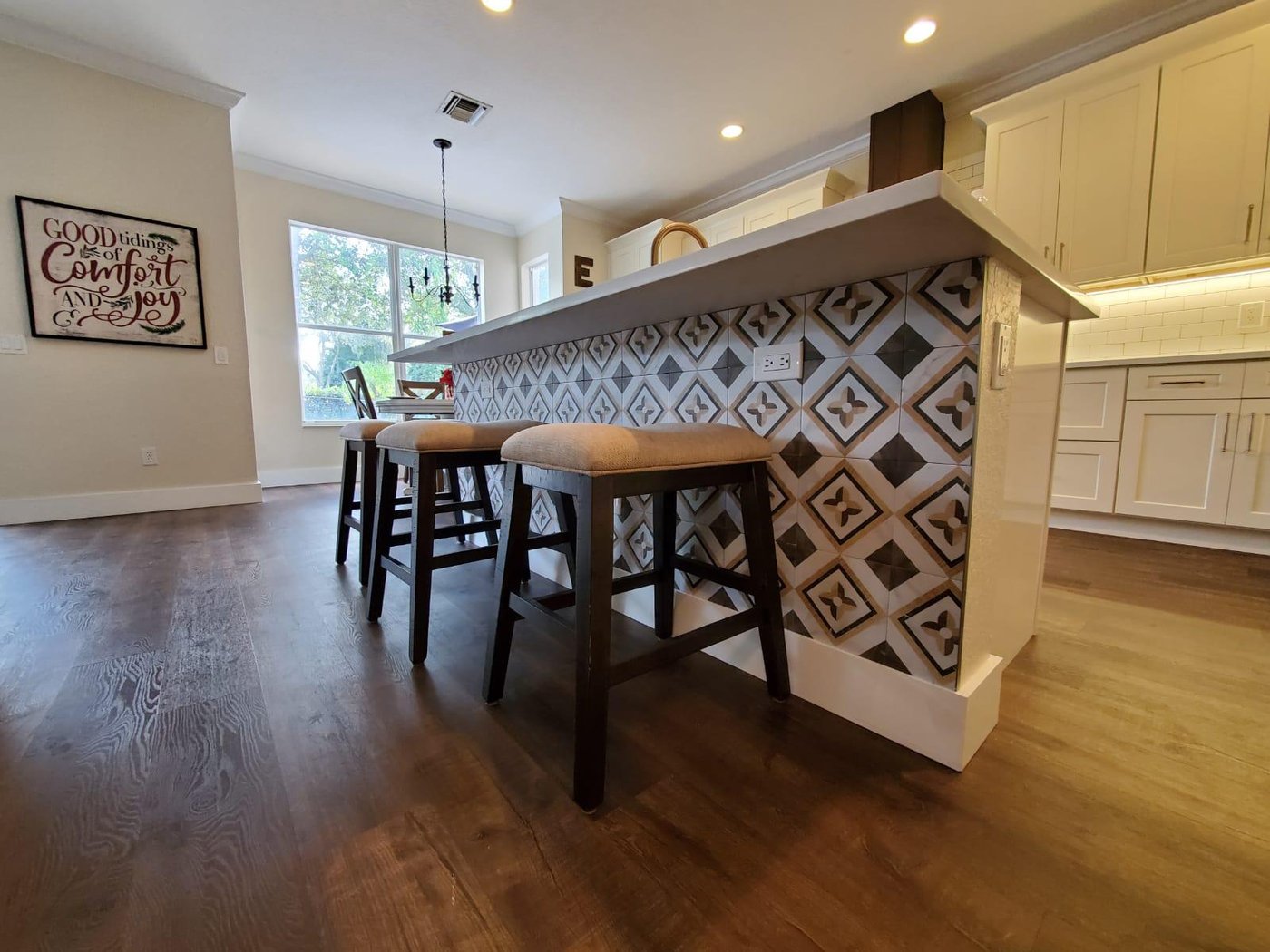 Detail of the kitchen island with patterned tile end-cap and counter-height stools