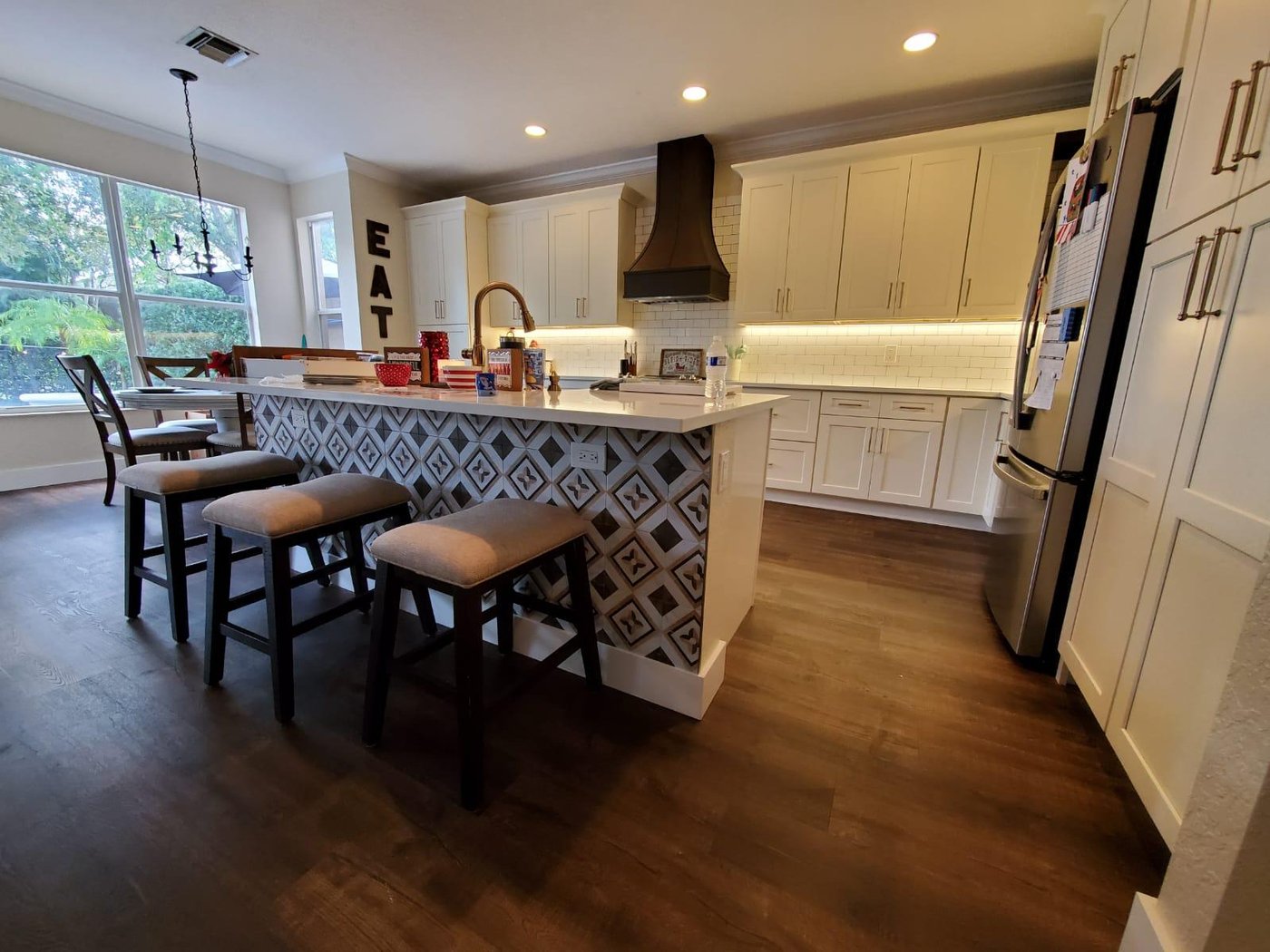 Renovated kitchen with white shaker cabinetry, natural wood island with patterned tile end-cap, and brass fixtures