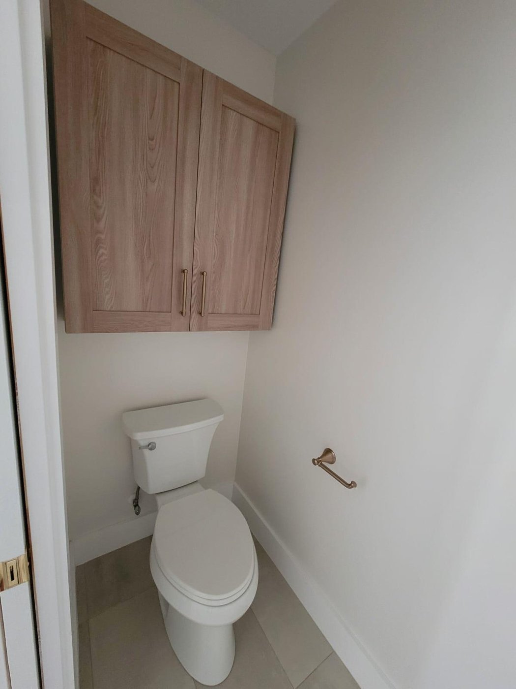 Enclosed toilet room with linen storage cabinet above