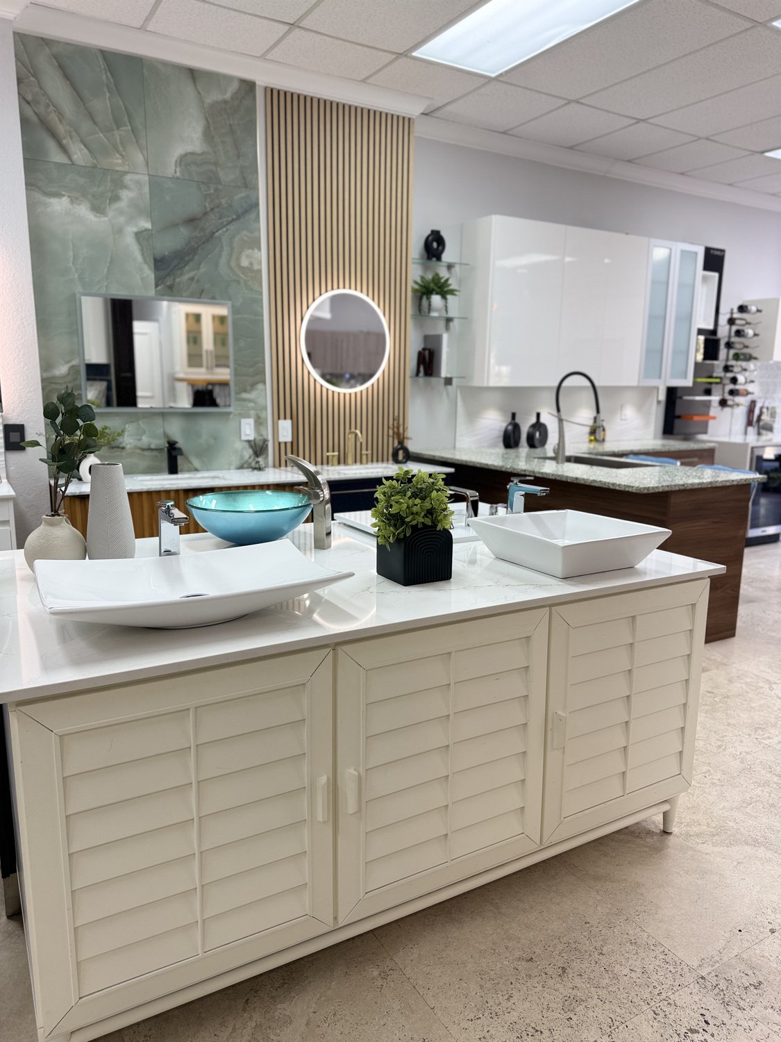 Showroom bath vignette: double white vanity with circular backlit mirrors and a wave-textured wall behind
