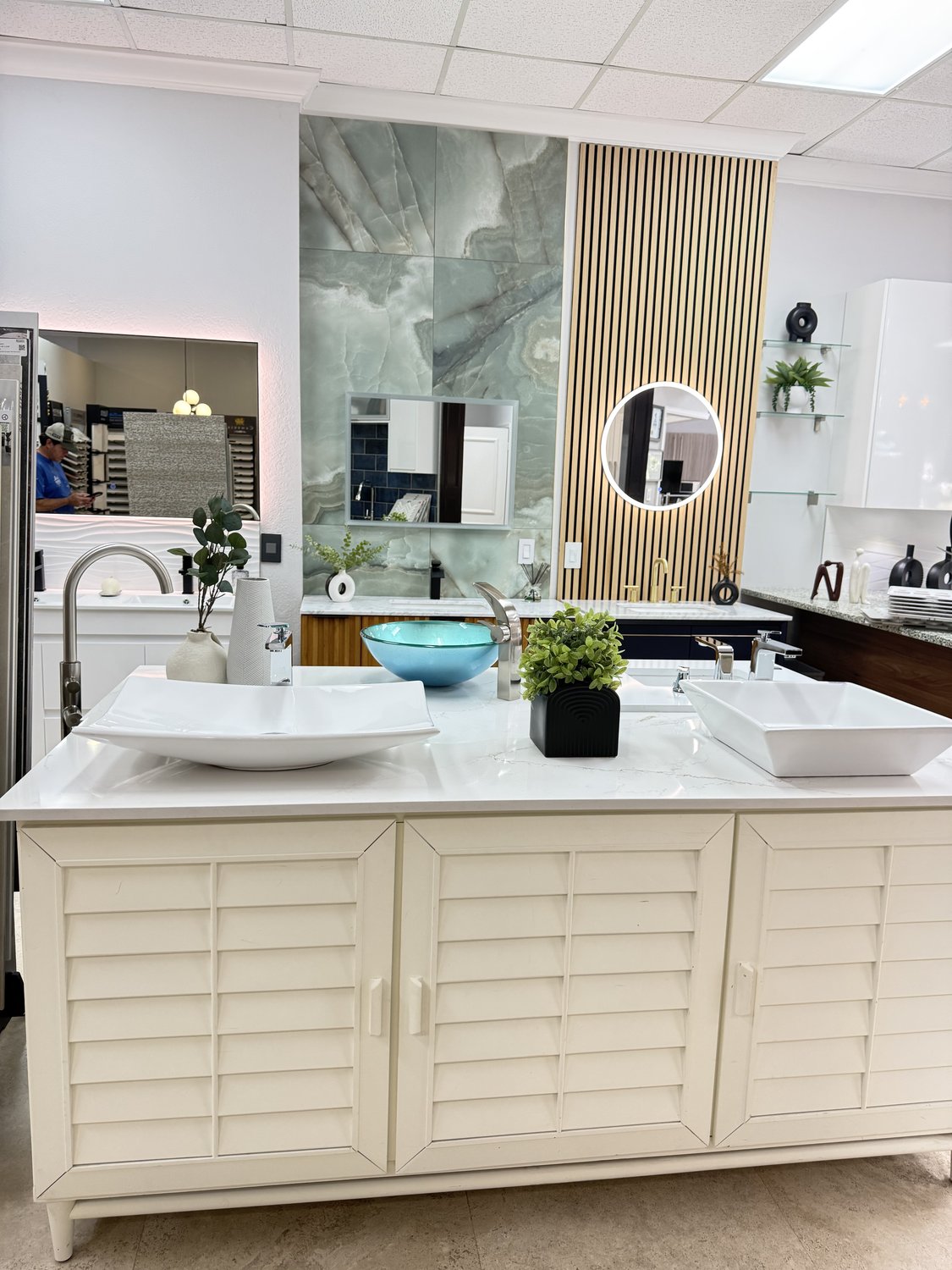 Showroom bath vignette with a white-shaker vanity, framed mirror, and stone-veined backdrop