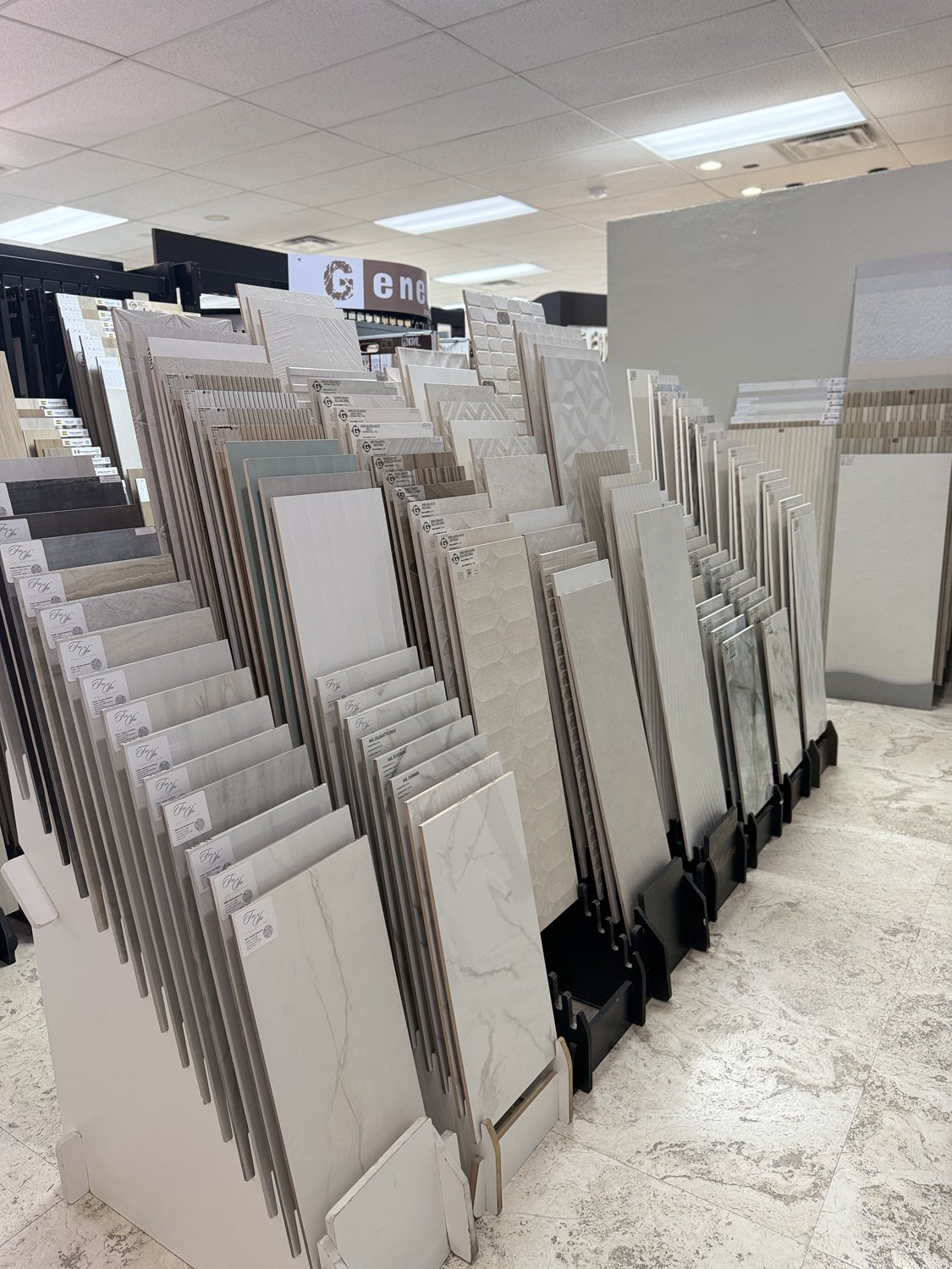 Tile sample wall in the showroom with side-by-side mounted swatches in marble, ceramic, and porcelain finishes