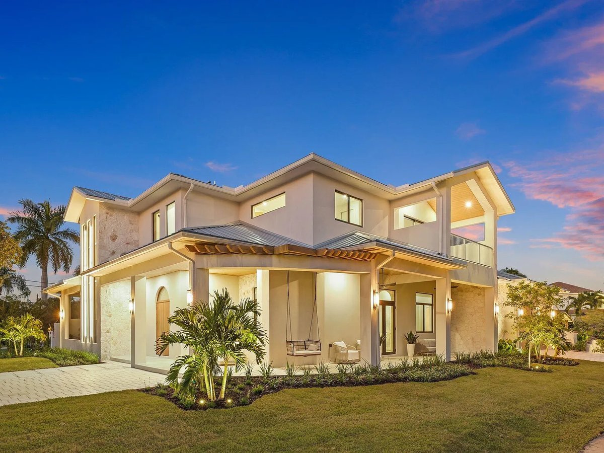 Twilight exterior of a Delray Beach home showing covered porch with hanging swing seats